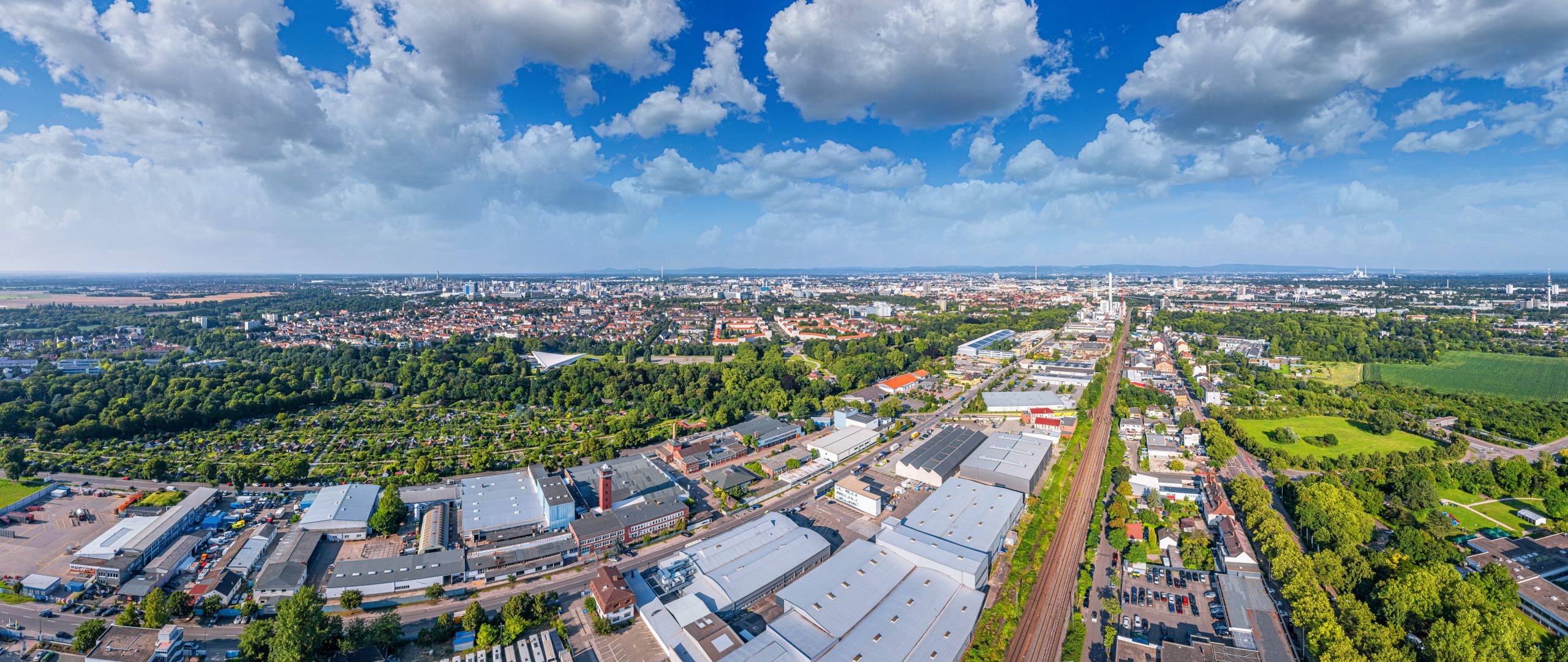 Stadtansicht mit dicht aneinanderstehenden Häusern und roten Dächern. Im Hintergrund sind Kirchtürme, eine Burg auf einem Hügel und ein moderner Turm zu sehen.